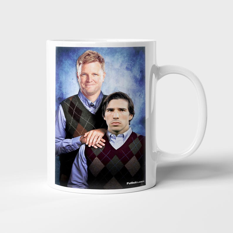 May include: White ceramic mug featuring a humorous image of two men in argyle vests and collared shirts against a blue backdrop. The mug has a handle on the right side and the text "FutbolClassics" is printed on the bottom.