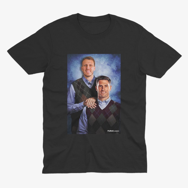 May include: A black t-shirt featuring a graphic of two men wearing sweaters. The men are smiling and standing next to each other. The background is a blue and white gradient.