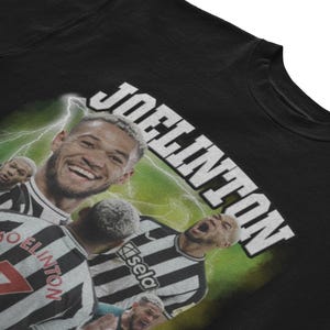 Pode incluir: Camiseta preta com um gr&aacute;fico de um jogador de futebol em um uniforme preto e branco. O nome do jogador, "Joelinton", est&aacute; escrito em letras brancas na parte superior da camiseta.