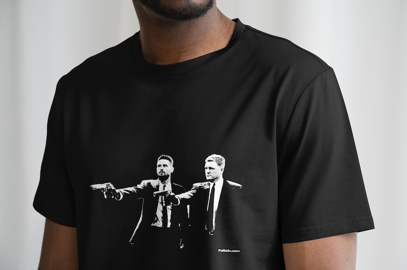 Puede incluir: Camiseta negra con un estampado gr&aacute;fico blanco de dos hombres con traje sosteniendo armas. El texto "Pulp Fiction" est&aacute; impreso en la parte inferior del gr&aacute;fico.
