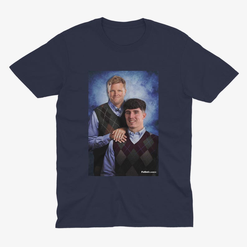 May include: A navy blue t-shirt with a photo of two men wearing sweaters. The men are standing in front of a blue and white background. The text "Puttin' on Classics" is printed on the bottom of the photo.