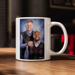 May include: A white ceramic mug with a black handle and the text "But First, Coffee" in a black, bold font. The mug is sitting on a wooden surface. The mug is approximately 4 inches tall.