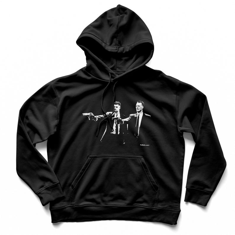 May include: Black hooded sweatshirt featuring a black and white graphic of two men in suits pointing guns. The image is centered on the front of the sweatshirt, with a kangaroo pocket and drawstring hood.
