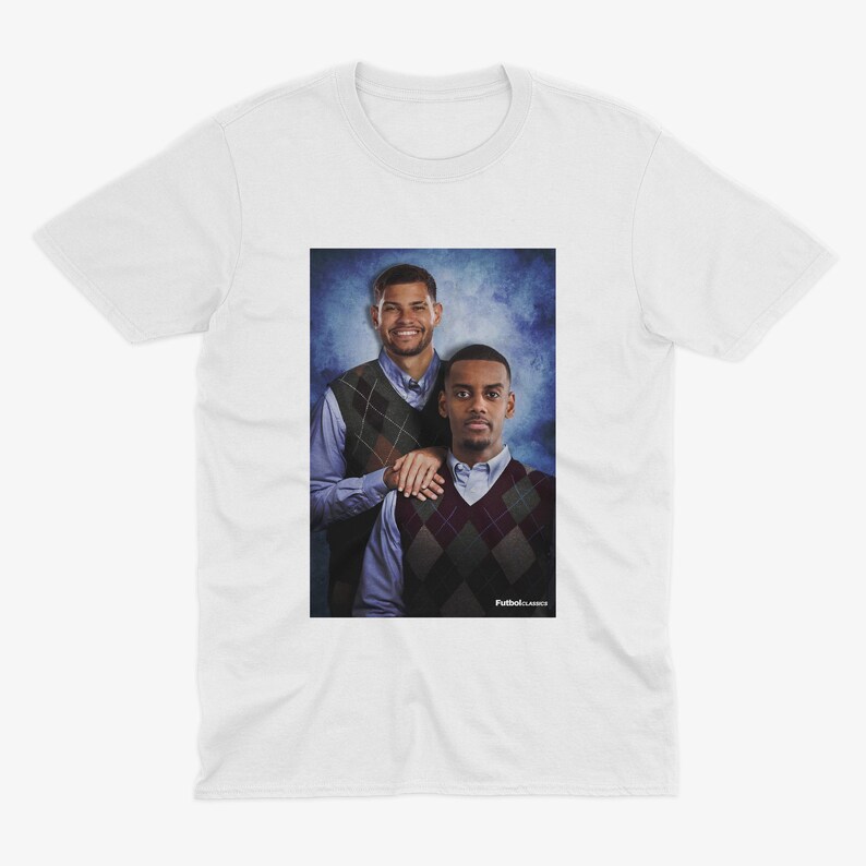 May include: A white t-shirt featuring a photograph of two men wearing sweaters. The men are standing in front of a blue and white background. The text "Putback Classics" is at the bottom of the photo.