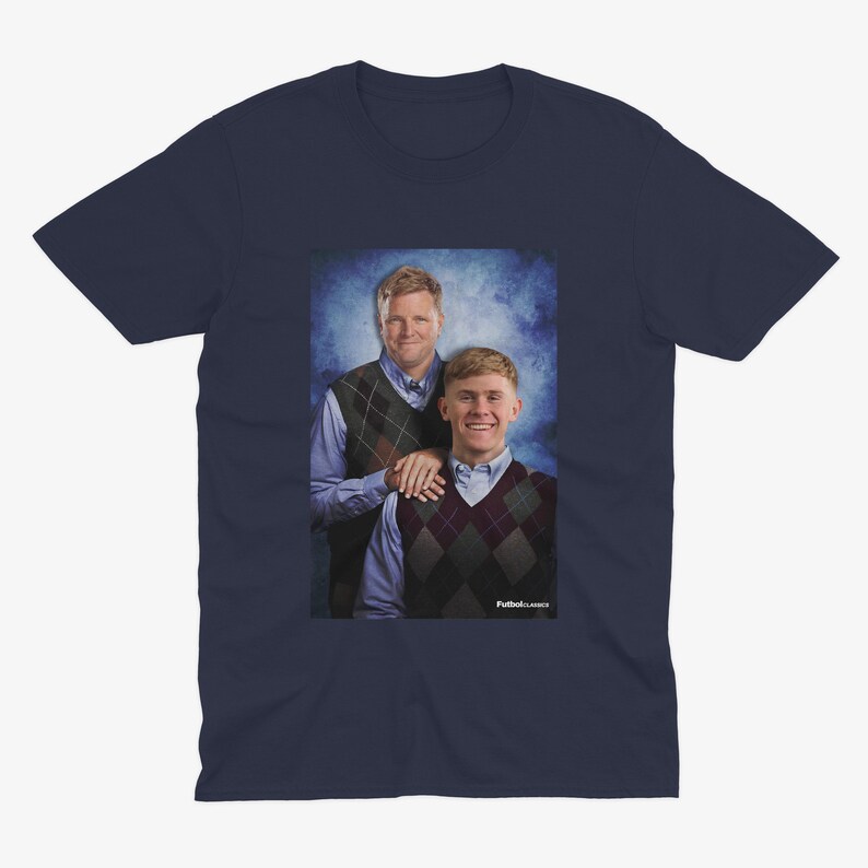 Pu&ograve; includere: Una t-shirt blu navy con una foto di due uomini con maglioni. L'uomo a sinistra indossa un maglione a motivi blu e bianchi, mentre l'uomo a destra indossa un maglione a motivi bordeaux e bianchi. Il testo "Puttin' on Classics" &egrave; in basso nella foto.