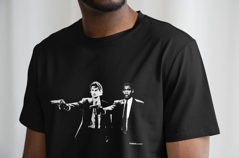 May include: Black t-shirt featuring a white graphic print of two men in suits, one pointing a gun. The text "Pulp Fiction" is printed at the bottom of the graphic.
