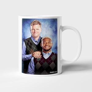 May include: White ceramic mug featuring a printed image of two men wearing argyle vests over button-down shirts. The image has a blue background and the text "FutbolClassics" is printed on the mug.