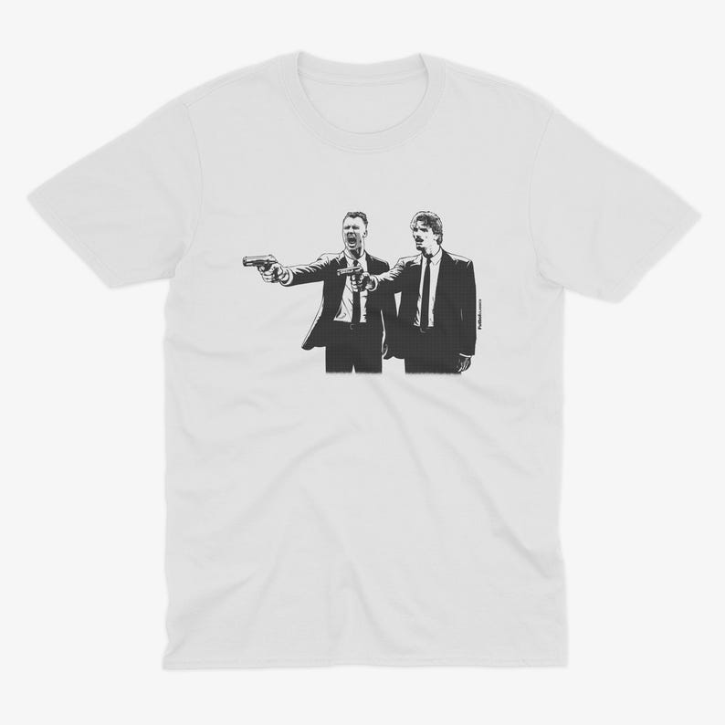 May include: White t-shirt featuring a black and white graphic of two men in suits pointing guns. The illustration is a stylized depiction of a scene from a film. The t-shirt is made of a soft, comfortable material.