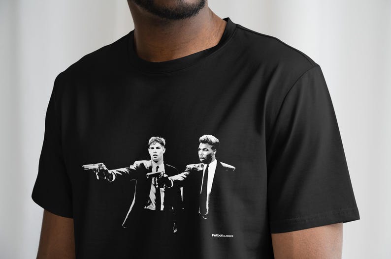 Op de afbeelding: Zwart T-shirt met een witte grafische print van twee mannen in pak die wapens vasthouden. De tekst "Pulp Fiction" is onderaan de print gedrukt.