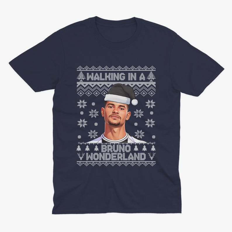 K&ouml;nnte beinhalten: Marineblaues T-Shirt mit weihnachtlichem Design. Das Shirt zeigt ein Portr&auml;t einer Person mit Weihnachtsm&uuml;tze, mit dem Text "WALKING IN A" dar&uuml;ber und "BRUNO WONDERLAND" darunter, umgeben von Schneeflocken und Weihnachtsb&auml;umen.