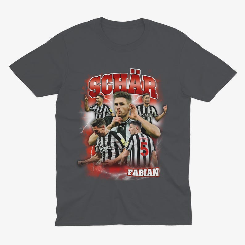 May include: A dark grey t-shirt featuring a graphic print of a football player, Fabian Sch&auml;r, in a black and white kit. The graphic has a retro style with red and white accents.
