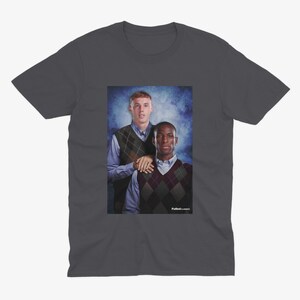 May include: A dark gray t-shirt with a photo of two men wearing sweaters. The men are standing in front of a blue and white background. The text "Fullback Classics" is at the bottom of the photo.
