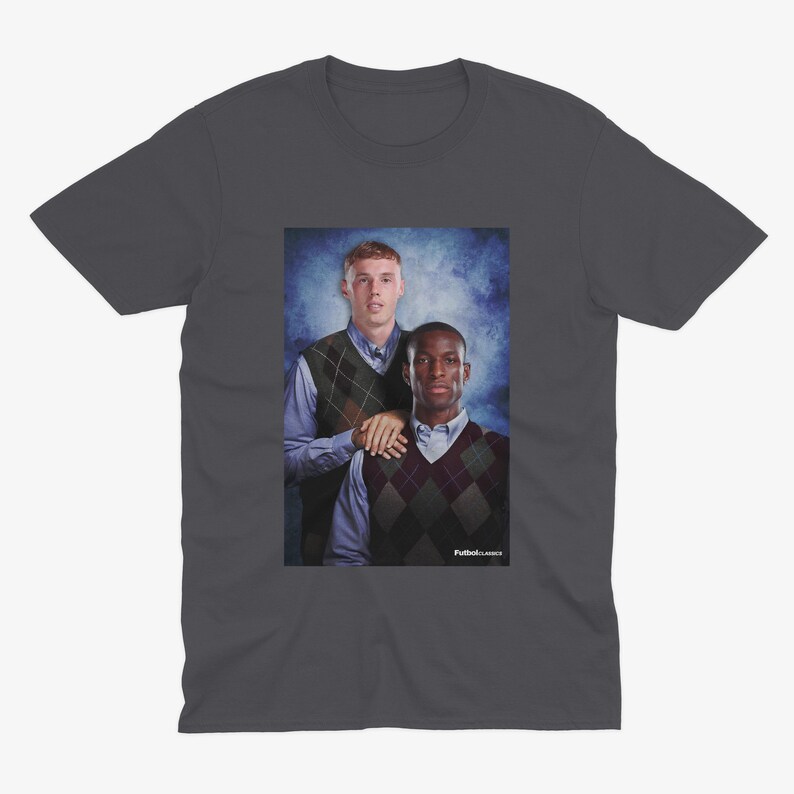 May include: A dark gray t-shirt with a photo of two men wearing sweaters. The men are standing in front of a blue and white background. The text "Fullback Classics" is at the bottom of the photo.
