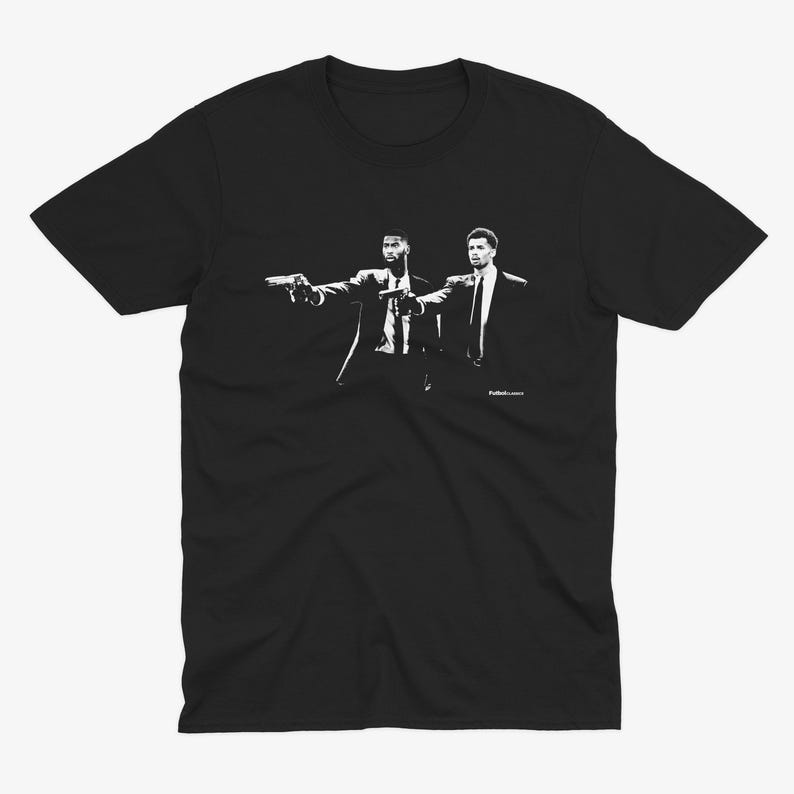 Op de afbeelding: Zwart-wit grafisch t-shirt met twee mannen in silhouet die wapens vasthouden. De tekst "Pulp Fiction" is gedrukt in de rechterbenedenhoek van het shirt.