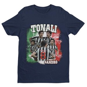 Puede incluir: Camiseta azul marino con un gr&aacute;fico de jugadores de f&uacute;tbol italianos. El gr&aacute;fico presenta a los jugadores con sus uniformes de equipo con el texto "TONALI" y "SANDRO" en la camiseta.