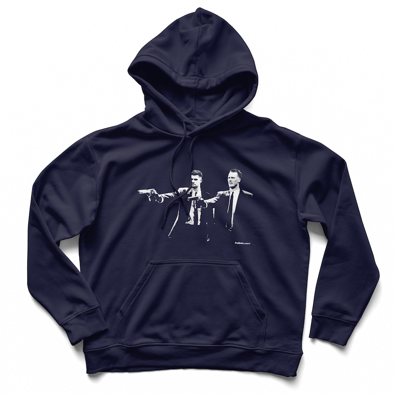 May include: Navy blue hoodie featuring a white graphic of two men pointing guns. The hoodie has a drawstring hood and a kangaroo pocket. The graphic is a stylized image of a scene from a movie.