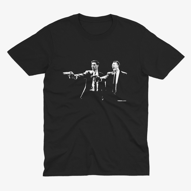 Puede incluir: Camiseta gr&aacute;fica en blanco y negro con dos hombres en traje apunt&aacute;ndose con pistolas. El texto "Pulp Fiction" est&aacute; impreso en letras peque&ntilde;as en la parte inferior del dise&ntilde;o.