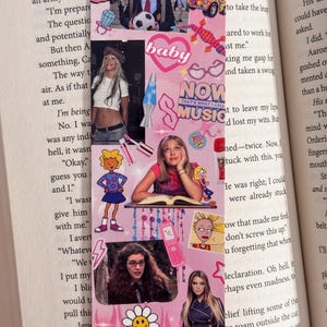 May include: Pink bookmark with various images and text, including a baby graphic, a lava lamp, and the words "NOW THAT'S WHAT I CALL MUSIC." The bookmark features images of celebrities and cartoon characters.