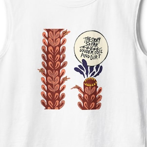 May include: White vest top with a vibrant illustration. The design includes two plant-like figures in brown, red, and orange, and a speech bubble with the text "THE STORY SO FAR UNDER SOIL AND DIRT".