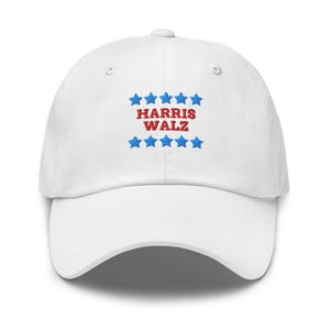 Könnte beinhalten: Weiße Baseballkappe mit rotem und blauem Sticktext "HARRIS WALZ" und blauen Sternen.