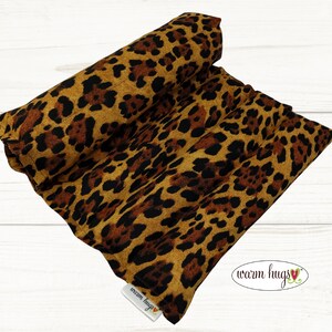 May include: A brown and black leopard print fabric hot pack with the text "warm hugs" on the bottom right corner.