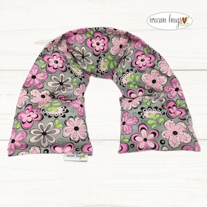 May include: A gray and pink floral patterned neck wrap with the text "warm hugs" on the bottom right corner and the top right corner.