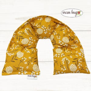 May include: A yellow neck wrap with a white floral pattern. The neck wrap is made of fabric and has a sewn-in pocket for a heating pad. The text "warm hugs" is printed on the neck wrap.