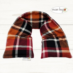 May include: A red, black, and orange plaid neck wrap with the text "warm hugs" on the tag. The neck wrap is made of soft fabric and is perfect for keeping warm in the winter.