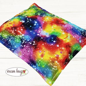May include: A rainbow-colored fabric with a galaxy print. The fabric has a white background with a variety of colors, including red, orange, yellow, green, blue, and purple. The fabric is covered in white stars and dots.
