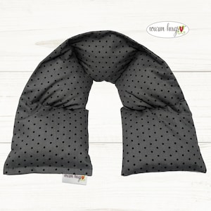 May include: Gray neck wrap with black polka dots. The wrap is made of soft fabric and has a sewn-in label that reads "warm hugs".