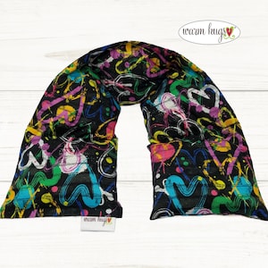 May include: A black neck wrap with a colorful abstract design featuring hearts and swirls in shades of pink, yellow, blue, and green. The wrap has a tag that reads "warm hugs".