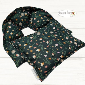 May include: A green neck wrap with a floral pattern. The wrap is made of fabric and has a sewn-in pocket for a heating pad. The text "warm hugs" is printed on the wrap.