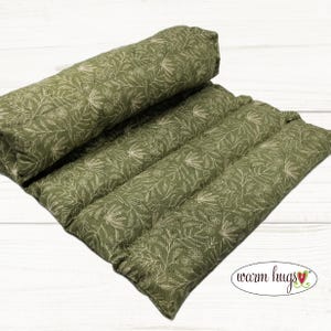 May include: A green and white floral patterned heating pad. The pad is rectangular with multiple quilted sections. The text "warm hugs" is printed on the bottom right corner. The pad is made of a soft, comfortable material.
