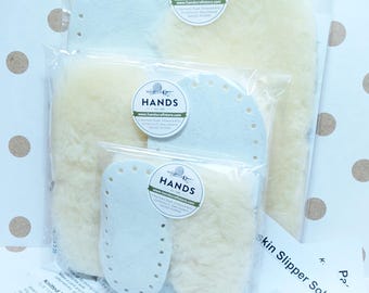May include: Three sets of sheepskin slipper soles in different sizes, packaged in clear plastic bags. Each bag has a white label with the text "HANDS" and a website address. The text "skin Slipper Soles" is visible on a white sheet of paper.