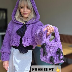 Peut inclure: Veste à capuche violette tricotée à la main et sac fourre-tout assorti. La veste a une coupe courte et une fermeture à pompon noire. Le sac fourre-tout présente des accents décoratifs noirs. L'image comprend le texte "FREE GIFT".