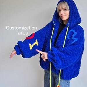 May include: A vibrant blue, hooded jacket with a plush, textured appearance. The jacket features yellow drawstrings with red tassels and colorful embroidered details. The text "Customization area" is visible in the image.