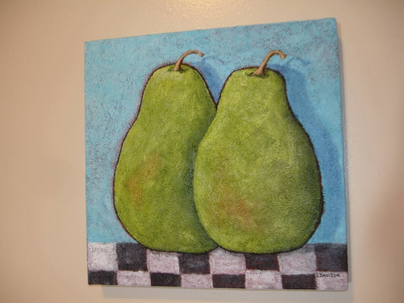 May include: A square painting features two green pears with brown stems against a textured blue background. The pears rest on a black and white checkered pattern. The artwork has a rustic, textured appearance.