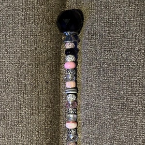 May include: A black and pink beaded charm bracelet with a black crystal top.