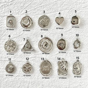 May include: A selection of silver pendants featuring celestial and symbolic designs. The pendants include suns, moons, and hearts, with sizes ranging from 10mm x 10mm to 18mm x 18mm. Each has a loop for a chain.
