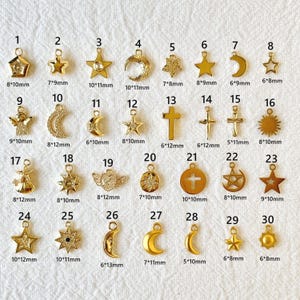 Pode incluir: Uma coleção de pingentes dourados com vários designs celestiais e religiosos. Inclui estrelas, luas, cruzes, anjos e raios de sol. Os tamanhos variam de 6 mm a 12 mm, perfeitos para fazer joias.