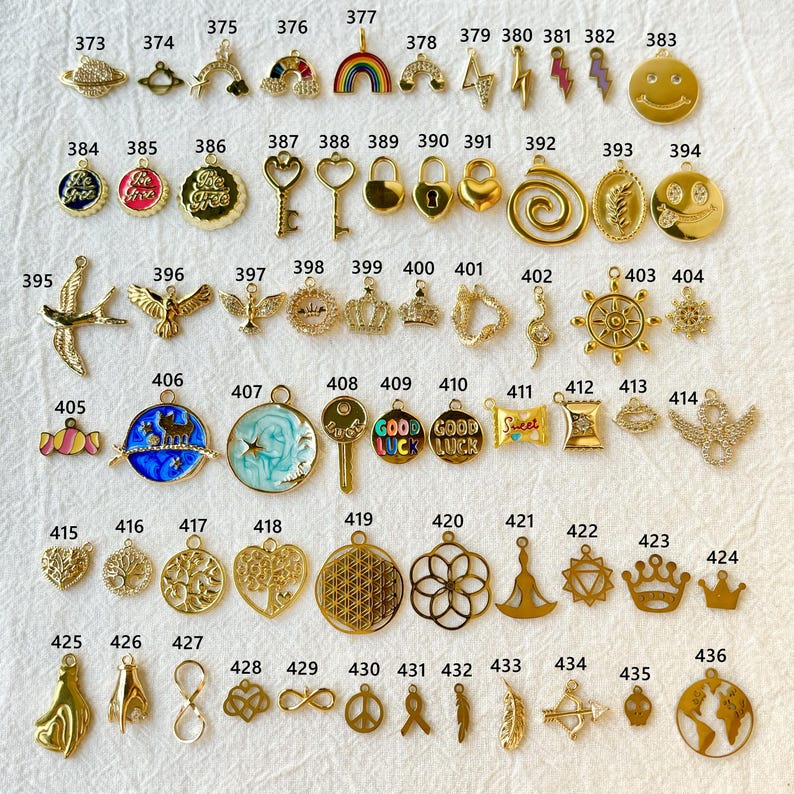 May include: A collection of gold-colored charms in various shapes, including a smiley face, lightning bolts, keys, crowns, and a world map. Some charms feature enamel details in colors like blue, red, and green. These charms are ideal for jewelry making.