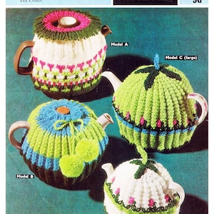 Op de afbeelding: Een vintage breipatroon voor vier verschillende thee-warmer ontwerpen. Het patroon is voor Sirdar 2518 en kost 9d. De ontwerpen omvatten een witte thee-warmer met roze en groene accenten, een groene thee-warmer met roze accenten, een blauwe en groene thee-warmer met groene pompoenen en een witte thee-warmer met roze en groene accenten.