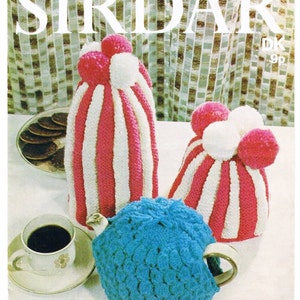 May include: A vintage knitting pattern for a teapot cozy and two matching tea cozy covers. The pattern is from the company "Sirdar" and is for a DK weight yarn. The covers are striped in pink and white and have white pom-poms on top. The teapot cozy is blue and has a crocheted texture.