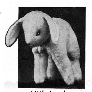 May include: A black and white photograph of a plush white lamb toy. The lamb is sitting on a black background and has its head down. The text "Little Lamb" is printed below the image.