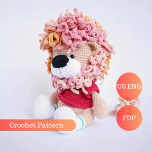 May include: Crochet pattern for a lion amigurumi toy. The lion is sitting with its legs crossed and has a pink and orange mane, a red shirt, and white shoes. The pattern is available in US English and PDF format.