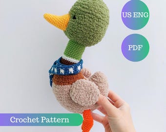 May include: A handmade crochet duck with a green head, yellow beak, and a blue and white scarf. The duck has a brown body and orange feet. The image includes the text "Crochet Pattern", "US ENG", and "PDF".