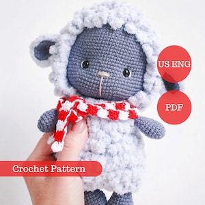 May include: Crochet pattern for a gray and white sheep amigurumi toy wearing a red and white striped scarf. The pattern is available in US English and PDF format.
