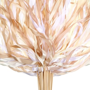 May include: A bunch of white and beige satin ribbon wands with wooden sticks. The ribbons are tied together at the top of the sticks.