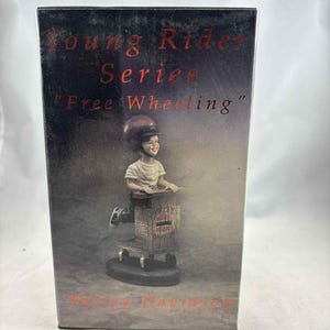 Puede incluir: Figura de Harley-Davidson de la "Young Rider Series". La figura representa a un niño con casco montando un patinete de madera. La caja tiene el texto "Free Wheeling" y "Harley-Davidson".