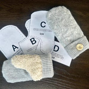 May include: A set of four sewing patterns for making mittens. The patterns are labeled A, B, C, and D. The patterns are printed on white paper and include instructions for cutting and sewing. The patterns are for sizes S/M.
